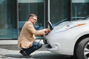 un' uomo d'affari addebiti un elettrico auto foto