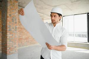 ritratto di uomo architetto a edificio luogo. fiducioso costruzione manager indossare elmetto protettivo. riuscito maturo civile ingegnere a costruzione luogo con copia spazio. foto