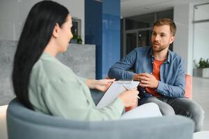 attività commerciale concetto. giovane dai capelli scuri donna seduta nel davanti di maturo allegro ufficio manager su lavoro colloquio, avendo rilassante parlare di sua Esperienza e studia livello. foto