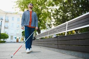 giovane bello accecato uomo a piedi con bastone nel cittadina foto