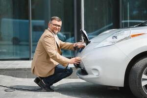 uomo addebiti un elettrico auto a il ricarica stazione foto