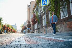 cieco uomo. persone con disabilità, portatori di handicap persona e ogni giorno vita. visivamente alterata uomo con a piedi bastone. foto