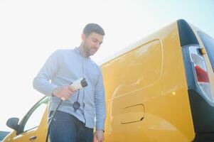 uomo ricarica il suo elettrico auto a caricare stazione. foto