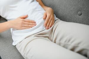 giovane donna sofferenza a partire dal addominale dolore a casa. ginecologia concetto foto