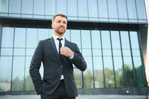 agente di cambio vicino il ufficio. un' riuscito e Avanzate bello attività commerciale uomo nel un' completo da uomo sembra su nel davanti di lui in piedi su il sfondo di calcestruzzo passi. foto