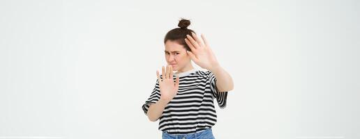 Immagine di donna rifiuto qualche cosa, raccolta mani nel difensiva gesto, proteggere se stessa, rifiutando offerta, in calo, in piedi al di sopra di bianca sfondo foto