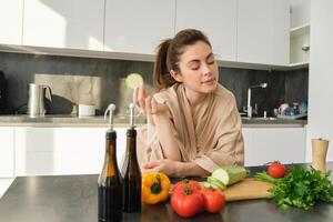 ritratto di brunetta donna, moglie cucinando a casa, fabbricazione cena, in posa vicino chopping tavola nel cucina con la verdura, Tenere zucchine foto