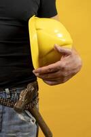 lavoratore con casco e utensili isolato su giallo sfondo. avvicinamento su il il petto foto