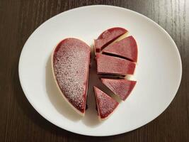 mousse tagliare torta nel il forma di un' cuore su un' bianca piatto. il concetto di San Valentino giorno, La madre di giorno, compleanno, celebrazione concetto. foto