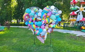 a forma di cuore design di elio palloncini nel un' estate parco. foto