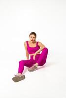 donna nel vivace rosa gli sport attrezzatura seduta su pavimento con uno gamba piegato foto