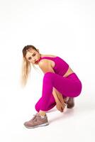 donna nel vivace rosa gli sport attrezzatura con uno ginocchio su pavimento e altro piegato nel davanti foto