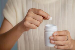 avvicinamento di donna mano Tenere bianca plastica bottiglia con pillole foto