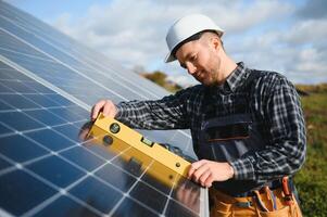 esperto è ispezionando qualità di un' solare batterie. lavoratore nel uniforme e casco con attrezzatura. ecologia energia conservazione concetto. foto