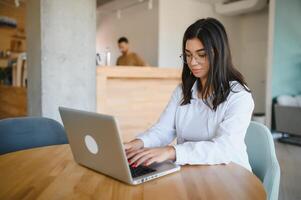 bellissimo caucasico donna sognare di qualcosa mentre seduta con portatile netbook nel moderno bar sbarra, giovane affascinante femmina libero professionista pensiero di nuovo idee durante opera su il computer portatile computer foto