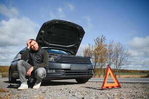 un' uomo sentire fatica perché il suo auto è rotto giù foto