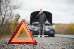 auto rotto giù su il strada, un' uomo chiamate il emergenza servizio, un' trainare camion. foto