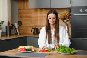 bellissimo giovane donna è preparazione verdura insalata nel il cucina. salutare cibo. vegano insalata. dieta. dieta concetto. salutare stile di vita. cucinando a casa. foto