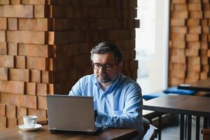 attività commerciale, tecnologia e persone concetto , anziano uomo d'affari con il computer portatile computer potabile caffè a moderno bar. foto