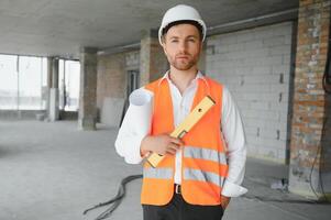 ritratto di uomo architetto a edificio luogo. fiducioso costruzione manager indossare elmetto protettivo. riuscito maturo civile ingegnere a costruzione luogo con copia spazio. foto