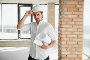 ritratto di uomo architetto a edificio luogo. fiducioso costruzione manager indossare elmetto protettivo. riuscito maturo civile ingegnere a costruzione luogo con copia spazio. foto