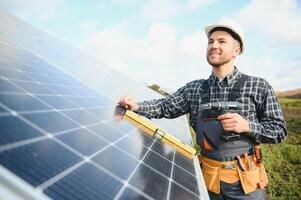 esperto è ispezionando qualità di un' solare batterie. lavoratore nel uniforme e casco con attrezzatura. ecologia energia conservazione concetto. foto