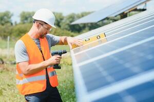 maschio lavoratore con solare batterie. uomo nel un' protettivo casco. installazione indipendente, autonomo solare pannello sistema foto