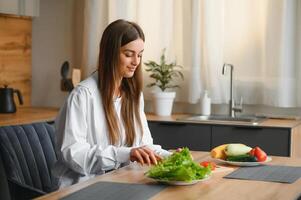 bellissimo giovane donna è preparazione verdura insalata nel il cucina. salutare cibo. vegano insalata. dieta. dieta concetto. salutare stile di vita. cucinando a casa. foto