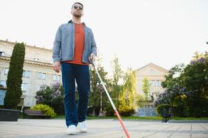 cieco uomo a piedi su marciapiede Tenere bastone foto