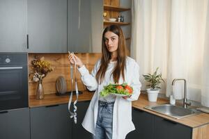 bellissimo giovane donna è preparazione verdura insalata nel il cucina. salutare cibo. vegano insalata. dieta. dieta concetto. salutare stile di vita. cucinando a casa. foto