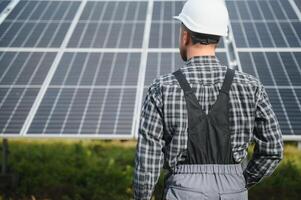 esperto è ispezionando qualità di un' solare batterie. lavoratore nel uniforme e casco con attrezzatura. ecologia energia conservazione concetto. foto