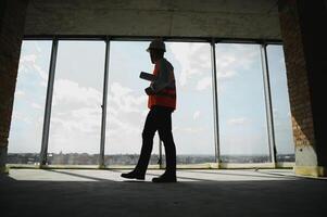 ritratto di un architetto costruttore studiando disposizione Piano di il camere, grave civile ingegnere Lavorando con documenti su costruzione luogo, edificio e casa ristrutturazione, professionale caposquadra a opera. foto