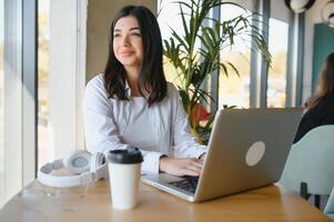 bellissimo caucasico donna sognare di qualcosa mentre seduta con portatile netbook nel moderno bar sbarra, giovane affascinante femmina libero professionista pensiero di nuovo idee durante opera su il computer portatile computer foto