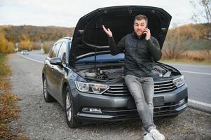 il auto rotto fuori uso, fuma a partire dal sotto il cappuccio, il autista scioccato foto