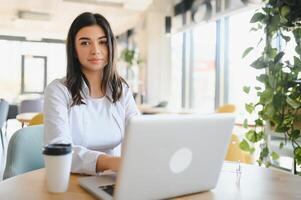 bellissimo caucasico donna sognare di qualcosa mentre seduta con portatile netbook nel moderno bar sbarra, giovane affascinante femmina libero professionista pensiero di nuovo idee durante opera su il computer portatile computer foto