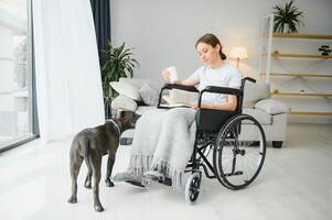 giovane donna nel sedia a rotelle con servizio cane a casa foto