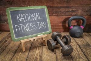 nazionale fitness giorno è celebre su il primo Sabato di Maggio nel noi, bianca gesso testo su lavagna con manubri e kettlebell foto