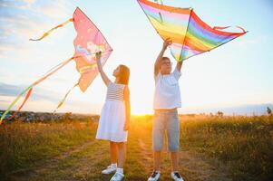 bambini lanciare un' aquilone nel il campo a tramonto foto