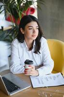 bellissimo caucasico donna sognare di qualcosa mentre seduta con portatile netbook nel moderno bar sbarra, giovane affascinante femmina libero professionista pensiero di nuovo idee durante opera su il computer portatile computer foto