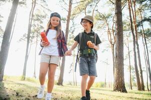 ragazzo e ragazza partire escursioni a piedi con zaini su foresta strada luminosa soleggiato giorno foto