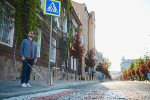 cieco uomo a piedi su marciapiede Tenere bastone foto