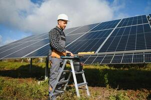 esperto è ispezionando qualità di un' solare batterie. lavoratore nel uniforme e casco con attrezzatura. ecologia energia conservazione concetto. foto