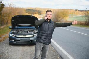 un' uomo sentire fatica perché il suo auto è rotto giù foto