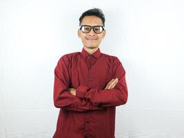 sorridente bello asiatico uomo nel casuale rosso camicia con braccio attraversato foto