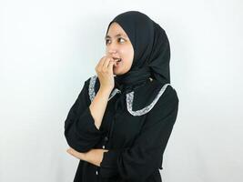 sorridente asiatico musulmano donna pungente dito e guardare a parte pensiero o avendo interessante idea foto