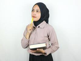 ritratto bellissimo asiatico donna nel hijab Tenere libro e penna, pensiero di qualche cosa. foto