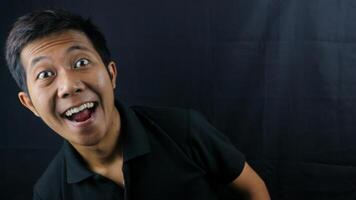 asiatico uomo con ridendo viso espressione su nero sfondo. foto