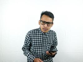 ritratto di asiatico uomo Tenere mobile Telefono con sorpreso viso espressione. foto