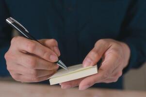 uomo d'affari mano utilizzando penna e appiccicoso Nota o inviare esso per scrittura un' Messaggio memorandum foto