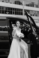 sposa con un' nero auto vicino un' bicchiere grattacielo foto